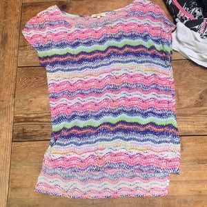 A very colorful short sleeve shirt, short in the front long in the back